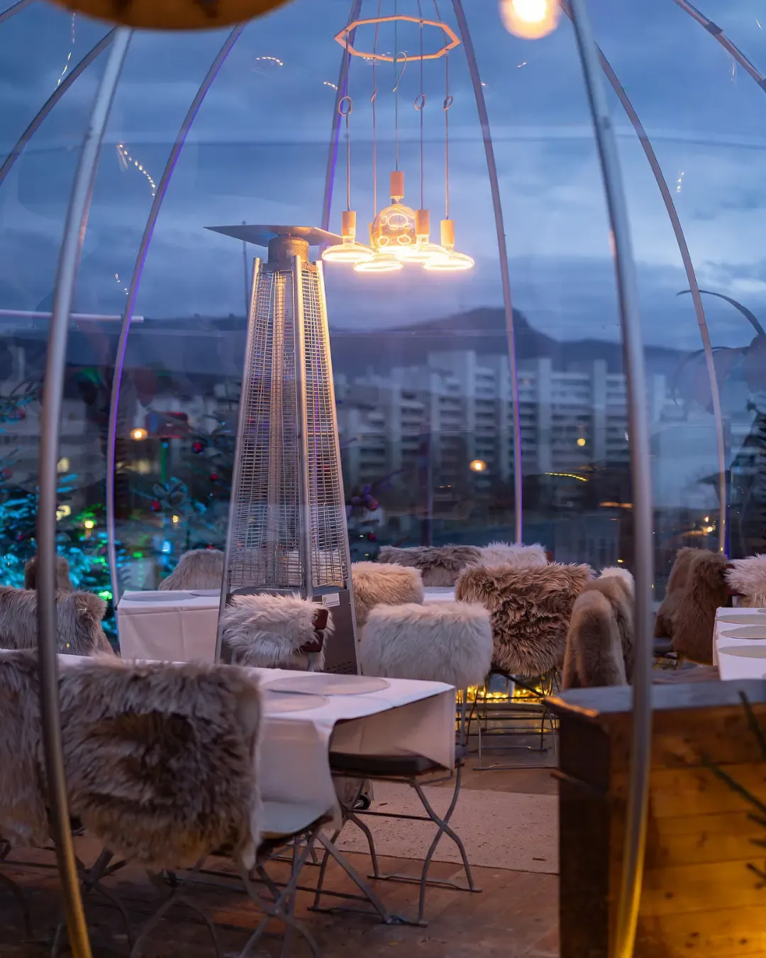 Iglu mit Fellstühlen, Heizstrahler und Blick über Aarau in der Abenddämmerung
