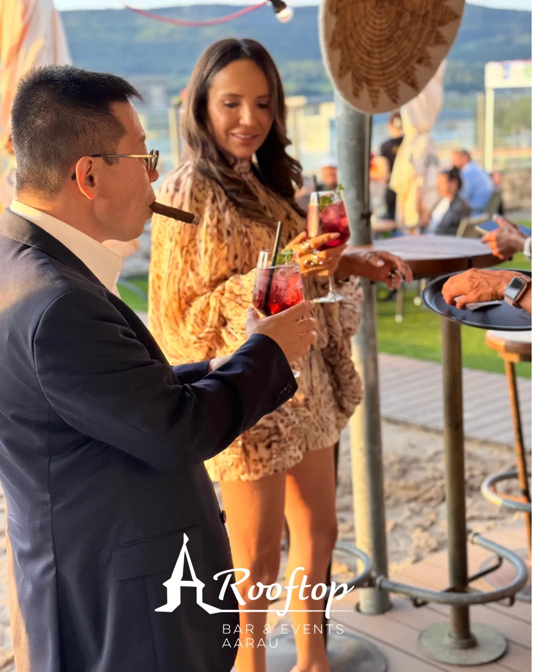 Gäste mit Sommerdrinks auf der Rooftop Aarau Terrasse bei Abendsonne