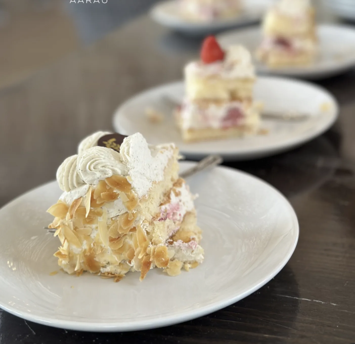 Feine Kuchenstücke mit Mandelblättern und Erdbeere als Dessert