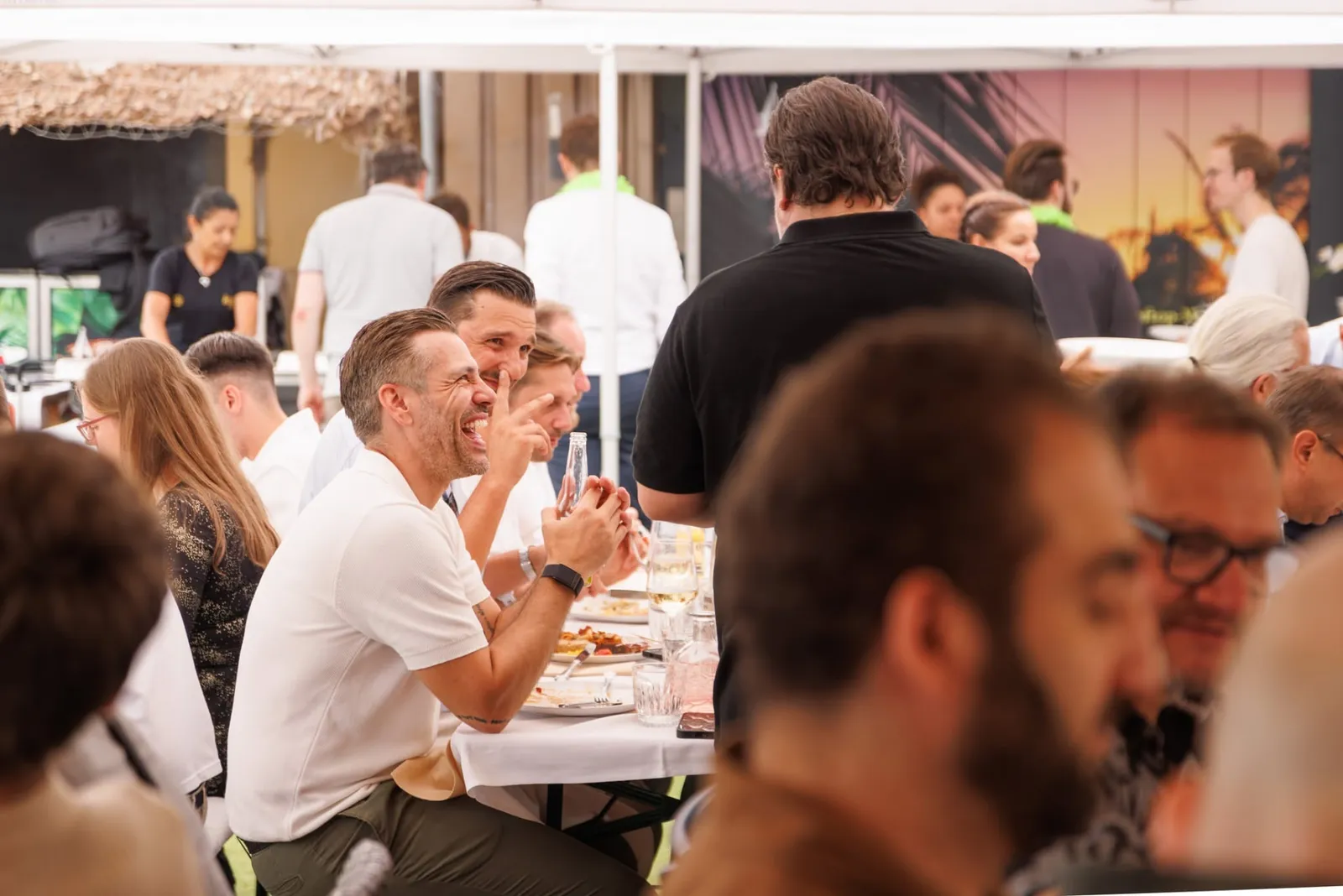 Lachende Gäste beim Essen an gedeckten Tafeln während eines Firmenevents im Rooftop Aarau