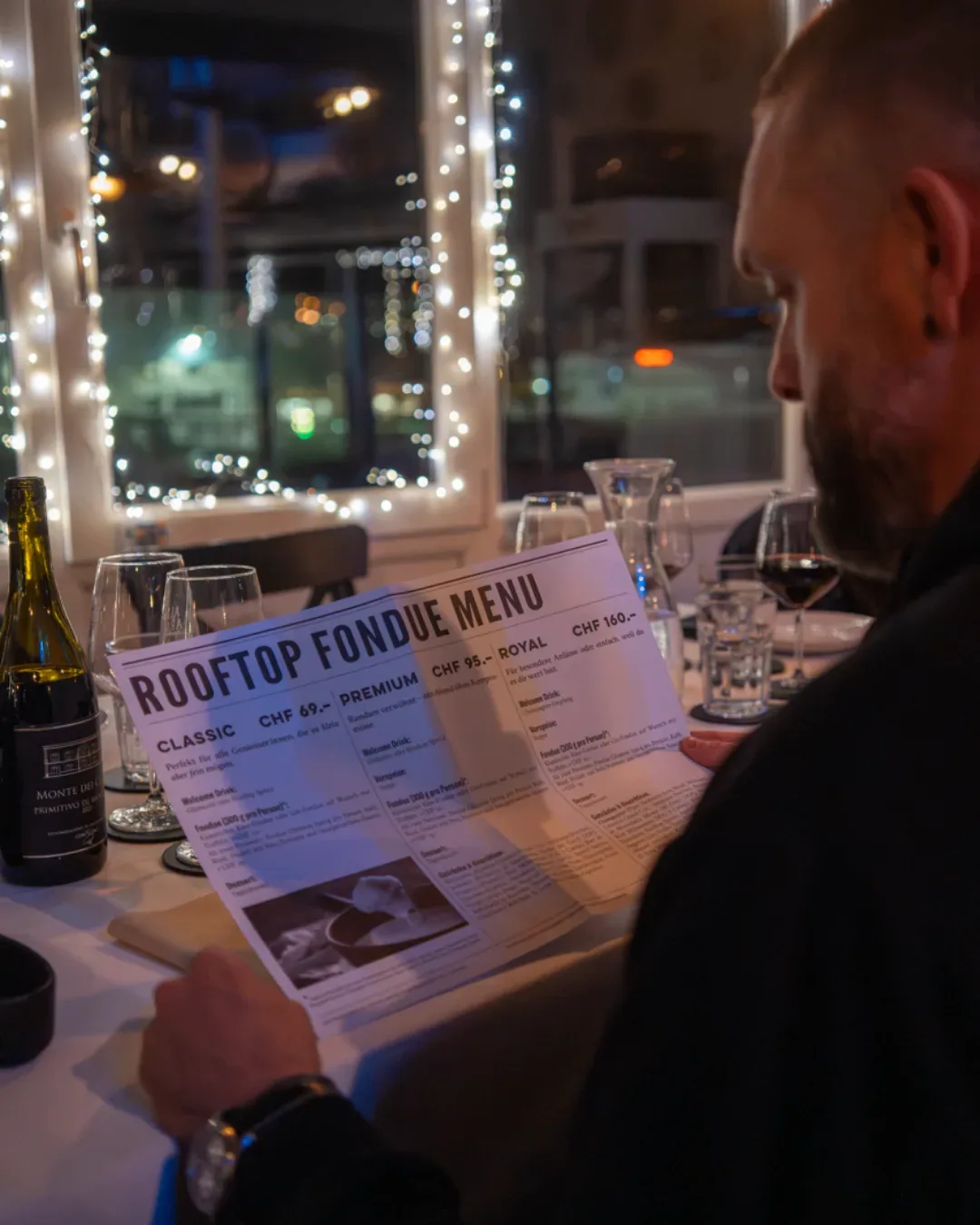 Gast studiert die Rooftop-Fonduekarte mit Käse-Fondue und Fondue Chinoise