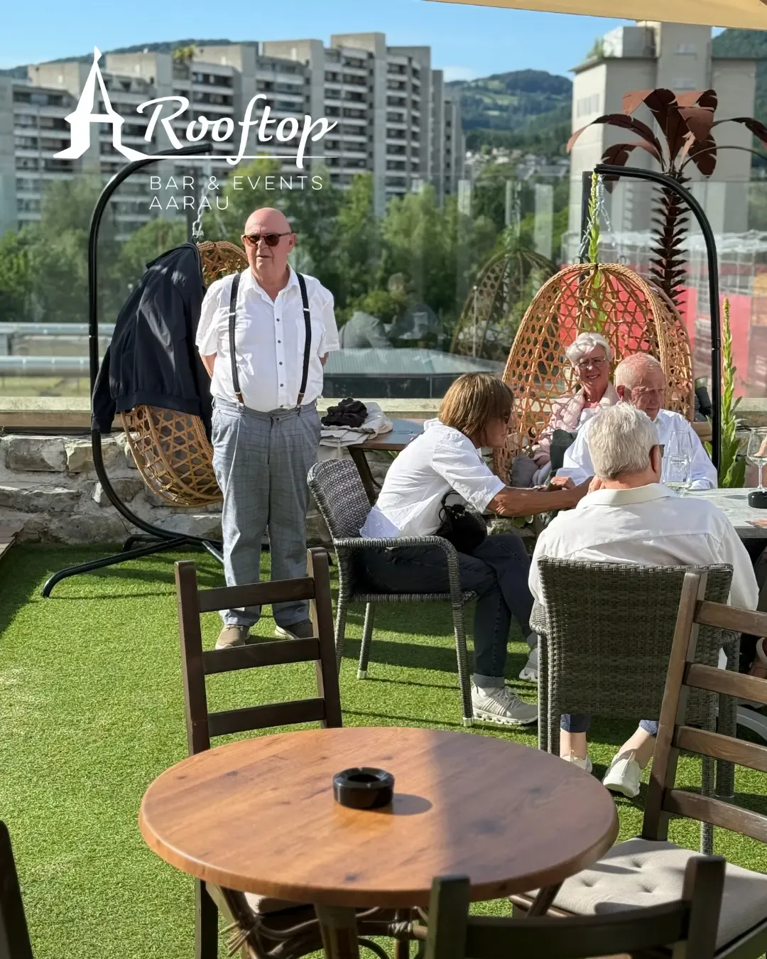 Gäste auf der begrünten Terrasse mit Hängesesseln und Blick über Aarau